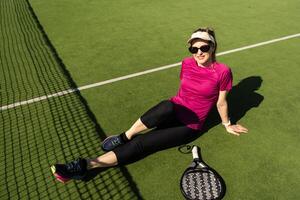 Happy female paddle tennis player during practice on outdoor court looking at camera. Copy space. photo