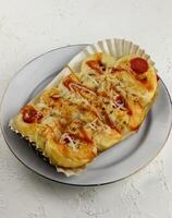 bread with sausage meat and spicy sauce, served on a white plate photo