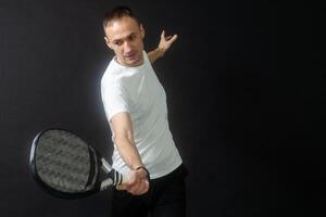 retrato de hombre jugando paleta tenis en posición a golpear un revés pelota negro aislado antecedentes. frente vista. foto