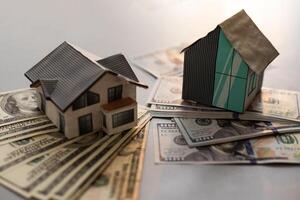 Miniature house model with banknotes on a wooden table, selective focus. Home loan concept. photo