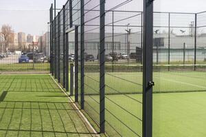 Tennis court with green grass and net outdoors photo