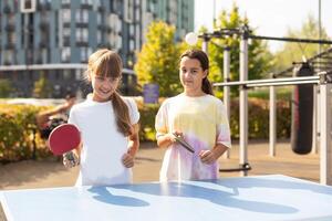 Kid playing table tennis outdoor with family photo