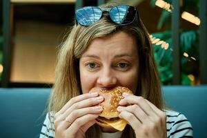 Woman eating burger, close up portrait photo