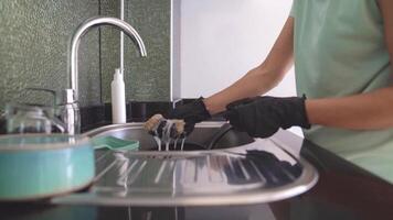 Girl applies ecological detergent to natural sponge for washing dishes, hands in black rubber protective gloves, concept of health and ecology care video