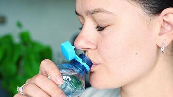 Young woman drinking from a bottle with stationary plastic cap. The new design means the cap remains attached to the bottle after opening, making the entire package easier to collect and recycle. video