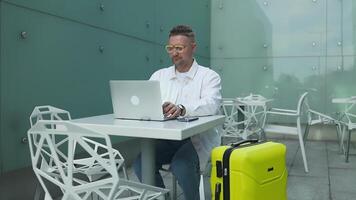 Travel, style Caucasian 30s man working checking on a laptop and waiting at terminal or boarding lounge. video