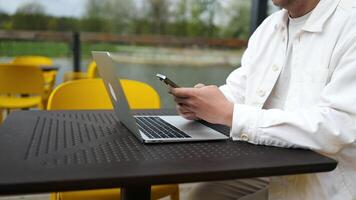 Close up of man wear casual clothes sits alone outdoors at table in coffee shop cafe work on laptop pc. Male has a call by phone, relax rest in restaurant during free time video