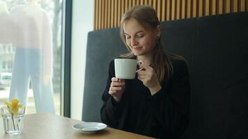 stänga upp av caucasian affärskvinna Sammanträde förbi de fönster dricka kaffe latte medan avkopplande i kaffe affär. skön kvinna njut av dricka kaffe på Kafé. små företag mat och dryck begrepp video