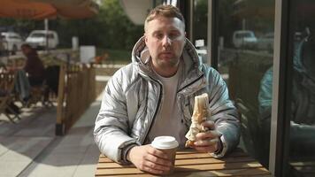 portrait de Beau Jeune caucasien homme en mangeant savoureux chaud chien séance dans en plein air café. livraison un service ouvrier avec savoureux nourriture video