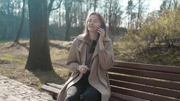 schön jung Frau verwenden Telefon Gehen beim Sonnenlicht Spaziergänge Nieder das zentral Stadt Straße, Dame sieht aus auf Sozial Medien mit Smartphone Gadget Gerät schleppend Bewegung. video