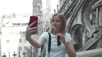 jung weiblich Tourist Herstellung Selfie Foto mit Clever Telefon auf das Dach von das berühmt Duomo Kathedrale im Mailand. glücklich Urlaube im Mailand video