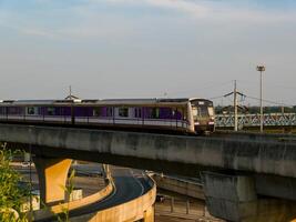 nonthaburi-tailandia abril dieciséis, 2024 el eléctrico cielo tren mrt púrpura línea pasa mediante central puerta oeste Departamento Tienda el más grande compras plaza en el noche a explosión sí, nonhaburi tailandia foto