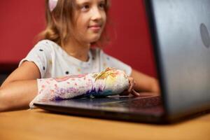 Teen girl with a broken arm orthopedic cast studying online photo