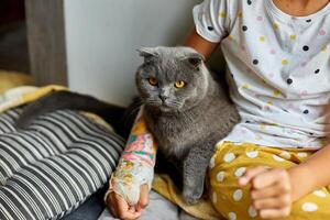 adolescente niña con un roto brazo ortopédico emitir jugar con gato foto