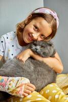 Teen girl with a broken arm orthopedic cast play with cat photo