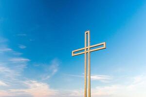 Golden cross against a background of blue sky with clouds. A minimalistic view of a gold-colored cross against the sky. photo