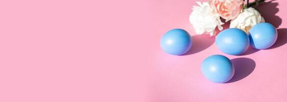 Easter eggs in blue on a pink background with flowers. photo