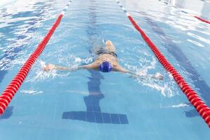 A pensioner of 70 years rests and swims in the pool in a clean, blue pool in the fresh air on vacation. photo