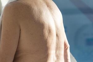 The back of an elderly man near a pool with clean water on the street. photo