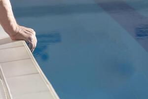 A man's hand near the pool with clear water on a sunny day. photo