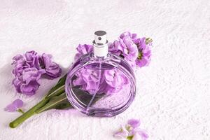 A chic bottle of women's perfume and a delicate lilac color flower. Front view. Unnamed bottle for product introduction. white background photo