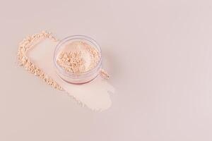 Open cosmetic jar with delicate loose powder on pastel background with powder swatch. A copy space. Product advertising. photo