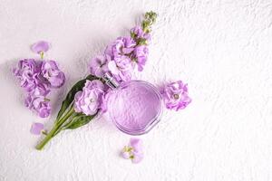 A chic round bottle with a delicate floral fragrance lies on a beautiful lilac flower. Top view. Blank product mockup. Packaging template. photo