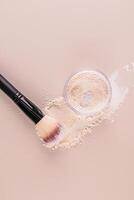 Loose light powder in a glass jar, powder swatch and chic black makeup brush on pastel vertical background. Top view. photo