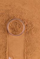 Top Vertical view of an open jar with loose powder of bronze tone stands on a scattered sample of powder. A copy space. Make up. photo