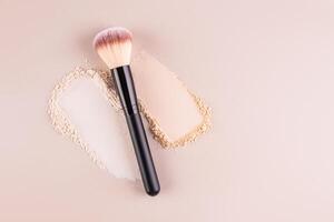 Two samples of loose powder in different tones and a makeup brush on a beige background. Top view. A copy of the space. Cosmetic background. Makeup. photo