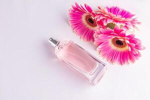 vaso botella de rosado perfume en blanco satín antecedentes con flores gerberas . el concepto de natural floral aromas parte superior vista. un Copiar espacio. foto