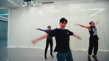 dos joven masculino bailarines practicando en un moderno danza estudio con blanco cortinas, mostrando energía y movimiento en un borroso video