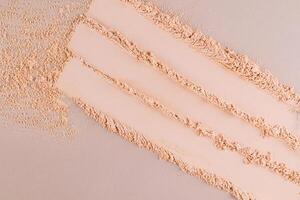 Three parallel stripes of a delicate texture of decorative face powder in a natural tone on a beige background. View from above. Swatch powder. photo