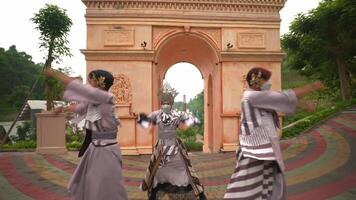 Tres intérpretes en tradicional japonés atuendo y cara mascaras danza en frente de un florido arco video