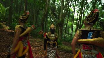 Three performers in traditional Balinese costumes and masks dancing in a lush forest setting, showcasing cultural heritage video