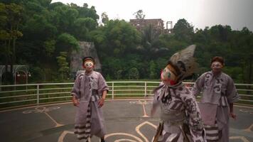 Traditional masked performers in elaborate costumes dancing outdoors with a natural and architectural background video