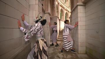 interprètes dans traditionnel costumes engageant dans une moquer bataille à l'intérieur un ancien pierre bâtiment avec arches et Colonnes, mettant en valeur culturel patrimoine video