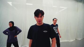 Three young dancers practicing in a modern dance studio with white curtains. They are dressed casually video