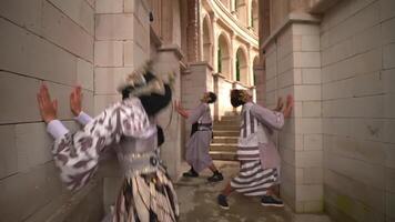 Three individuals in traditional Asian attire and face masks standing in an ornate stairwell, showcasing a blend of cultural heritage video