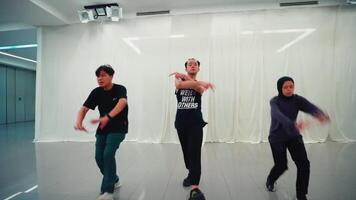 Tres hombres practicando danza se mueve en un estudio con espejos, enfocado y en movimiento, con uno hombre en el primer plano. video