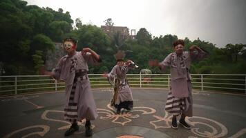 Traditional masked performers in vibrant costumes dancing outdoors with a lush green backdrop, showcasing cultural heritage video