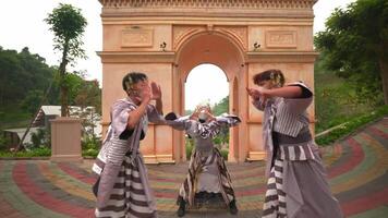 Three individuals wearing traditional Japanese yukata and face masks walking through a park with an ornate arch structure video