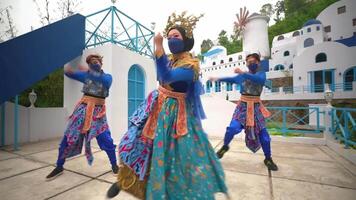 Dancers in colorful costumes performing traditional dance in front of a Santorini-inspired backdrop video