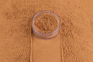 an open jar with loose powder of bronze tone stands on a scattered sample of powder. A copy space. Concept of cosmetics , make up. Top view photo