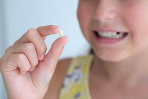 The girl is holding her milk tooth in her hands. Child happy after tooth extraction. photo