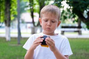 The child eats a black burger on the street. The boy bites off pieces of a cheeseburger. Fast food photo