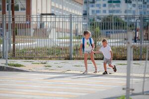 Brother and sister run across a pedestrian crossing. Children Run along the road to kindergarten and school.Zebra traffic walk way in the city. Concept pedestrians passing a crosswalk photo