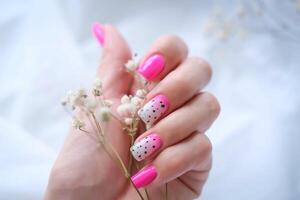 Women's hands with a fashionable pink manicure hold dried flowers in their hands. Spring - summer nail design photo