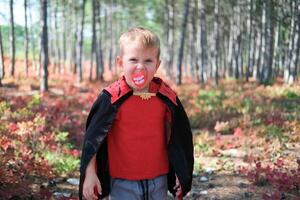 Funny kid in carnival costume outdoors. A boy in a Halloween costume scary looking at the camera. photo