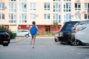 A schoolgirl girl runs with a briefcase on her back to school. Back to school. photo